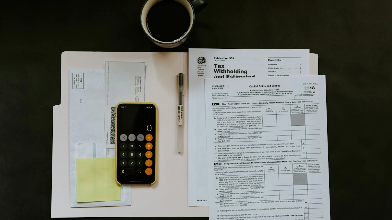 Tax forms next to a calculator and pen on a white desk