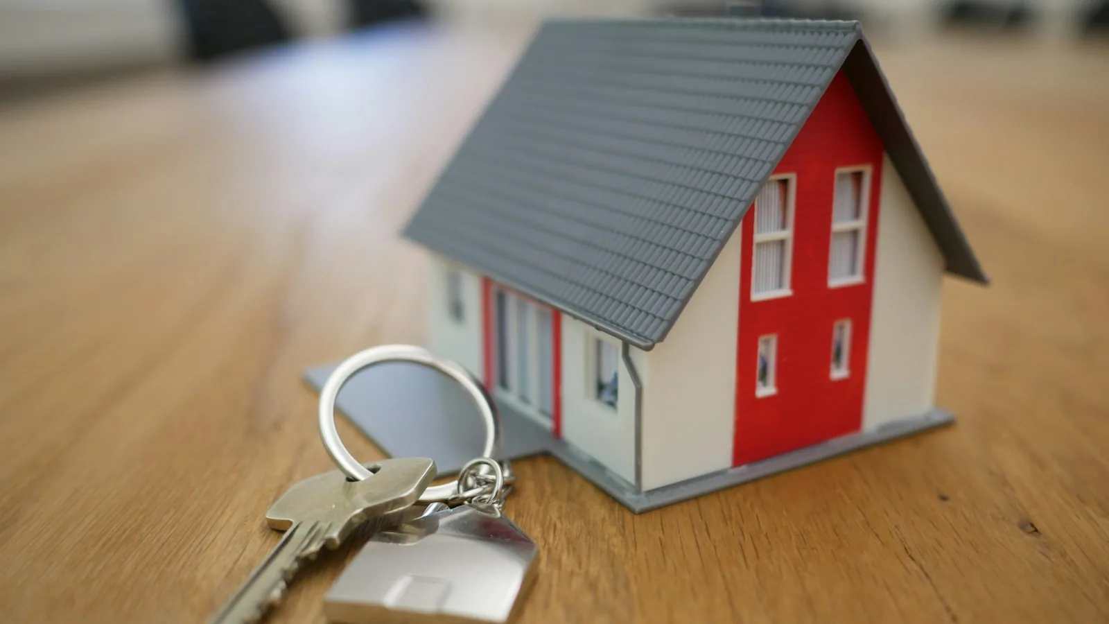 Two hands exchanging keys over a signed real-estate contract
